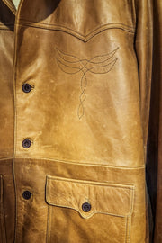 Suede tan jacket with embroidered detailing on display against a wooden background.