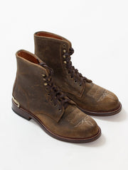 A pair of worn brown leather lace-up boots on a white background.