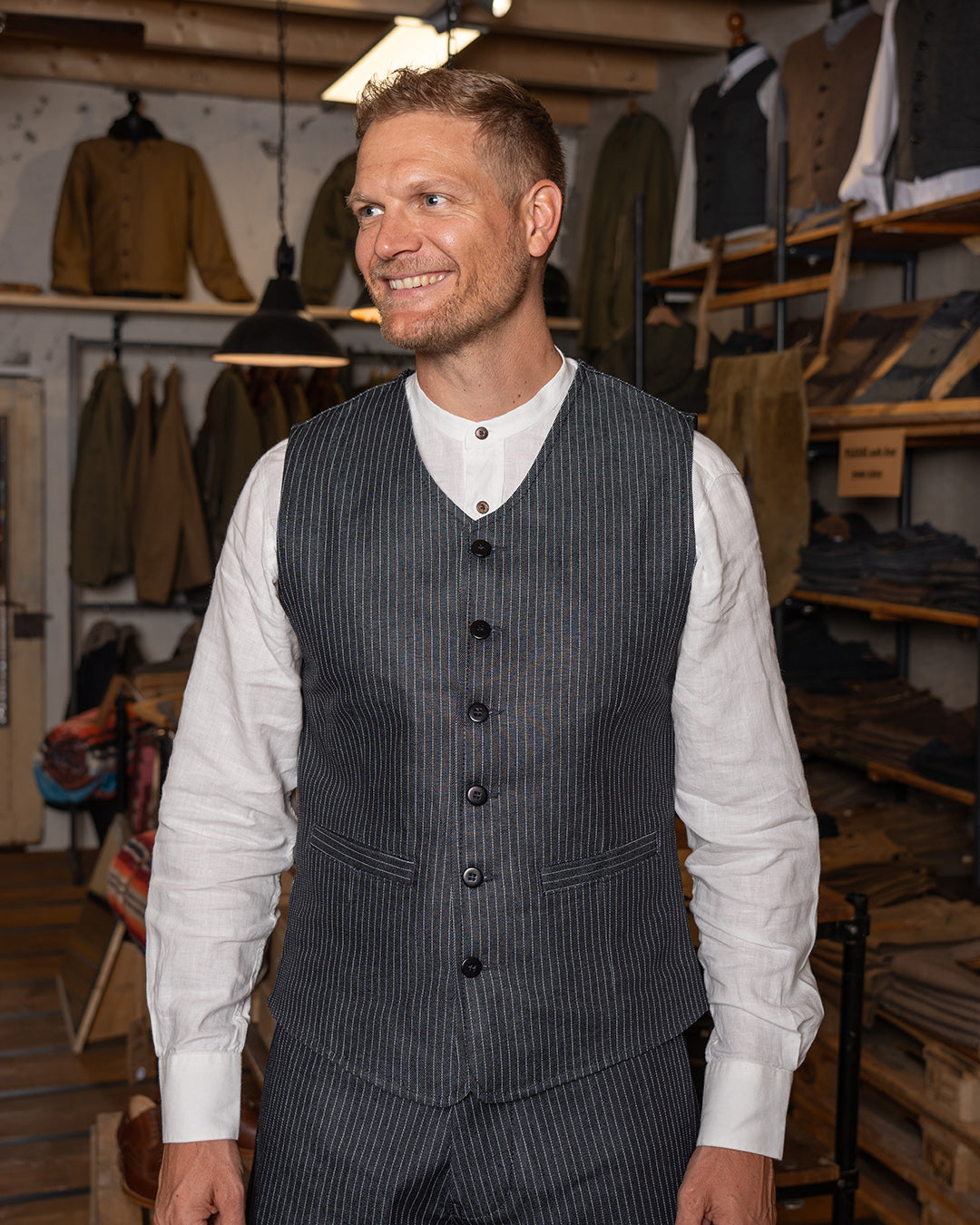 A man wearing a pinstripe navy blue vest with a button-down front and two pockets