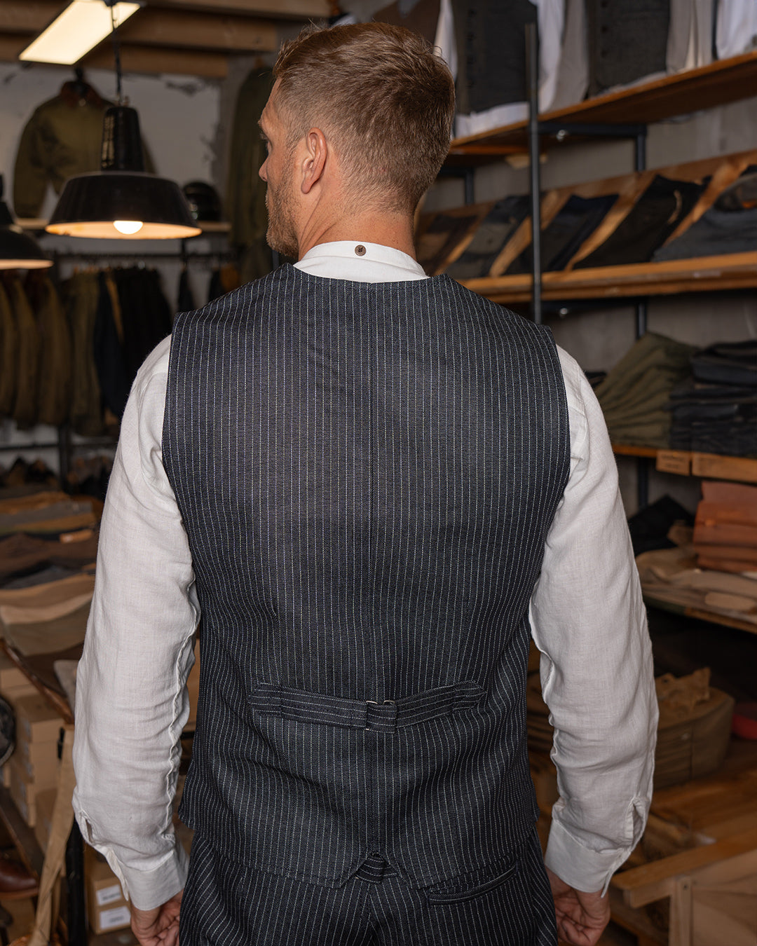 A man wearing a pinstripe navy blue vest with a button-down front and two pockets