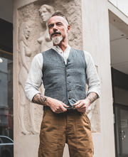 A man wearing a gray pinstriped vest with buttons and front pockets 